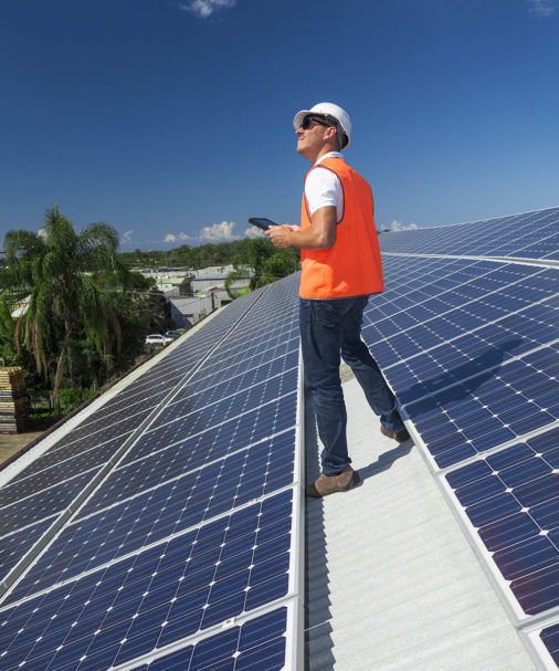 Young technician installing solar panels on factory roof